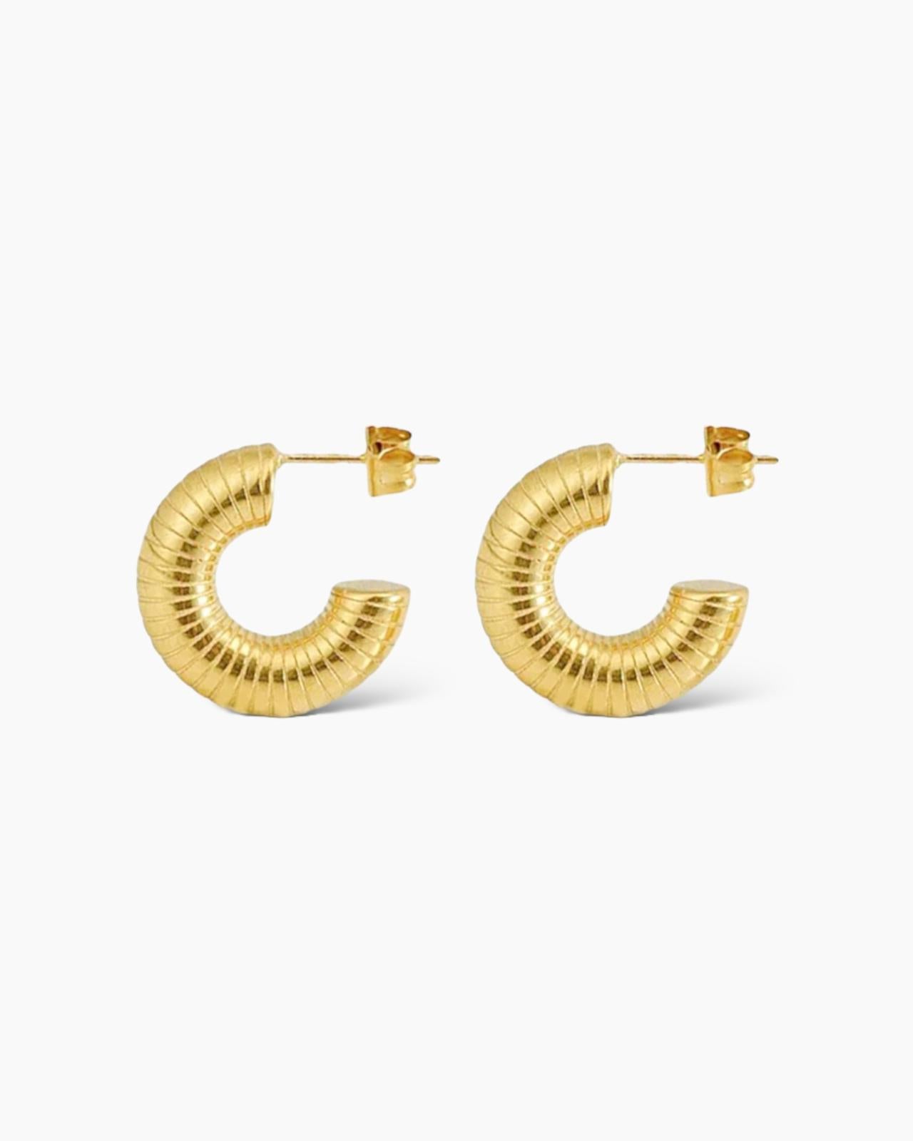 Los pendientes Aros Fio son unos aritos de tamaño grande, super gruesos y con forma estriada de rayitas. En acero inoxidable y acabados en oro de18k.