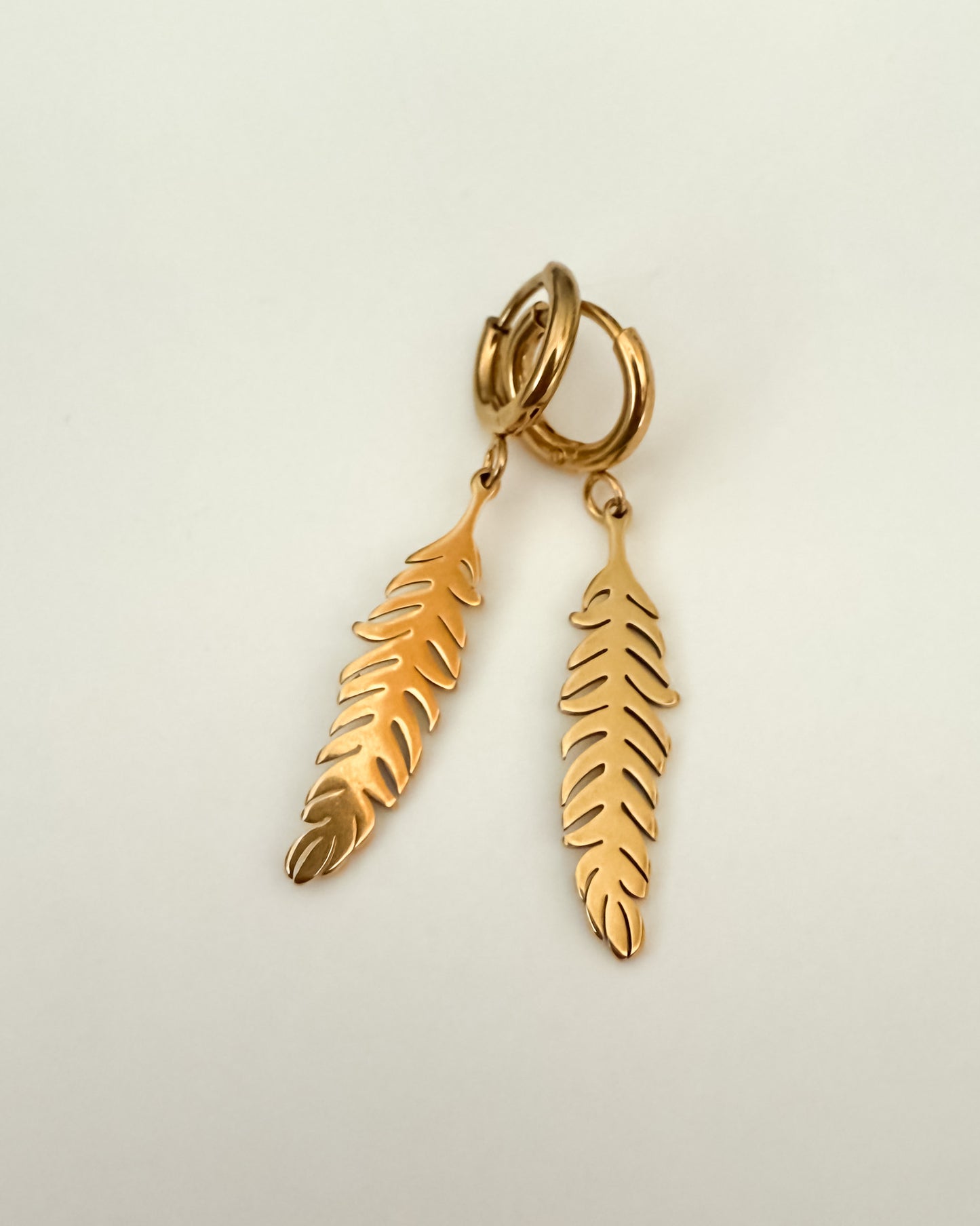 Aritos con charm diseño pluma en acero inoxidable baño oro 18K Pluma