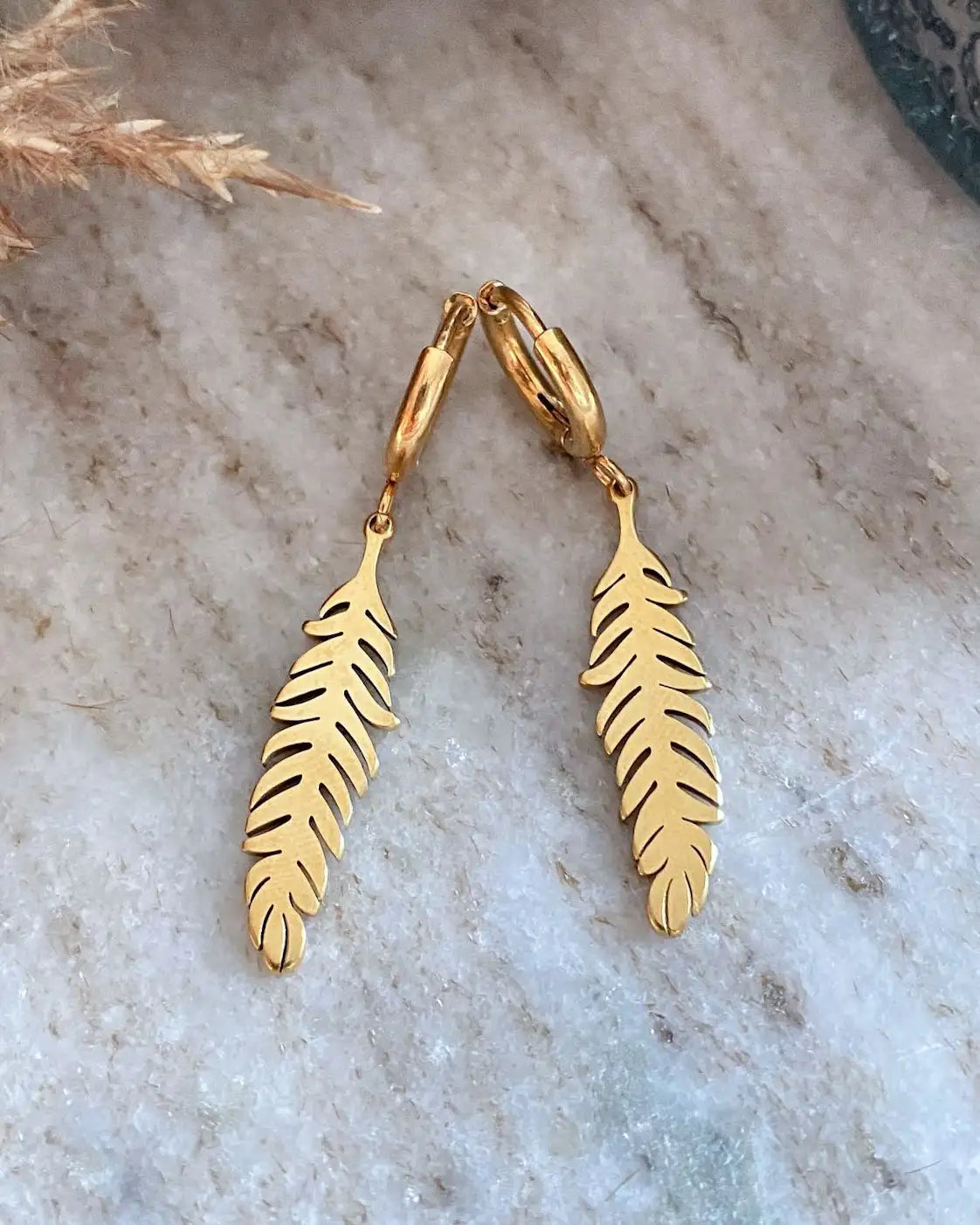 Arito con colgante con diseño de pluma, en acero inoxidable bañado en oro de 18k.