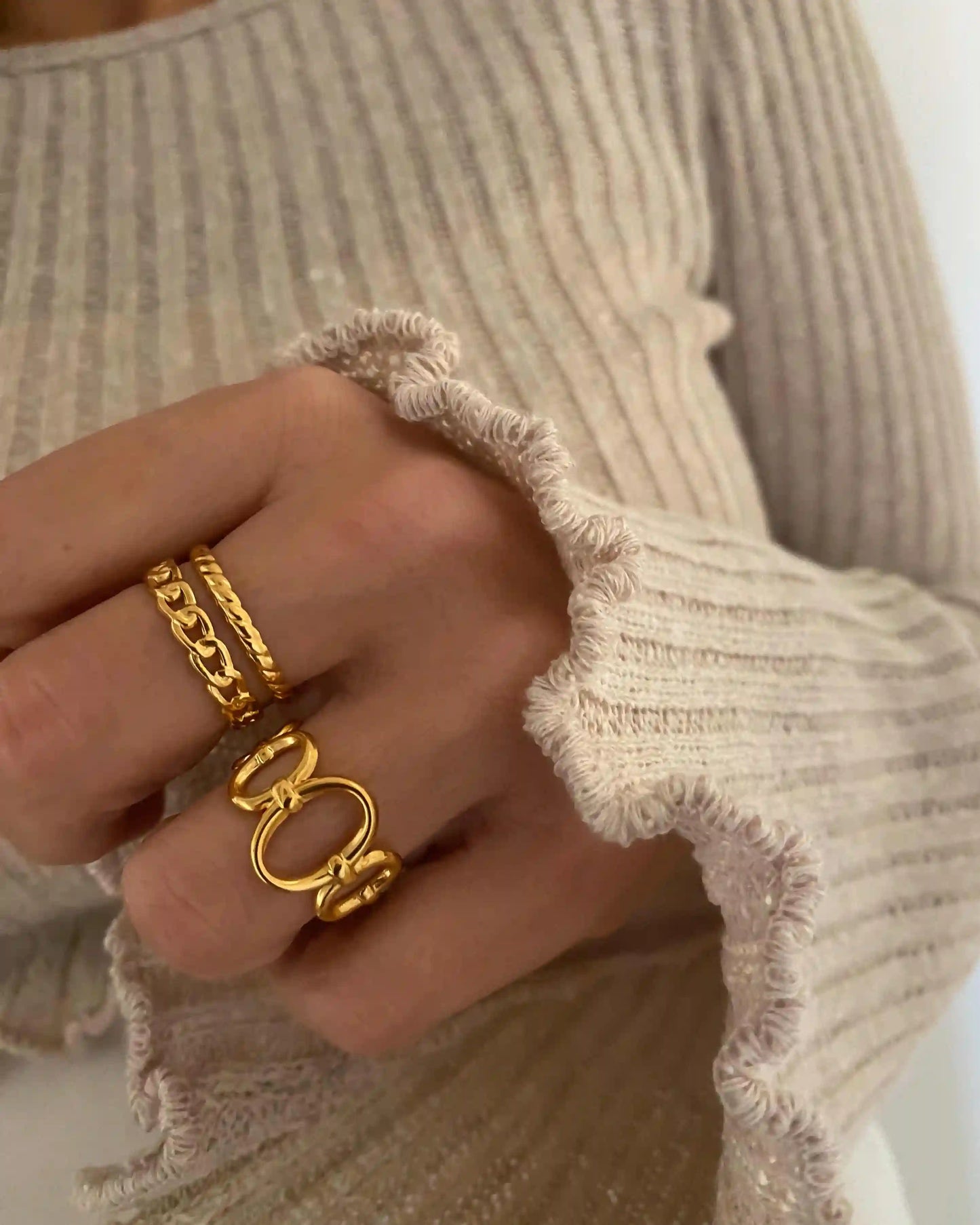 Anillo ajustable doble aro, uno con forma trenazada y otro con forma de cadena, de acero inoxidable bañado en oro.