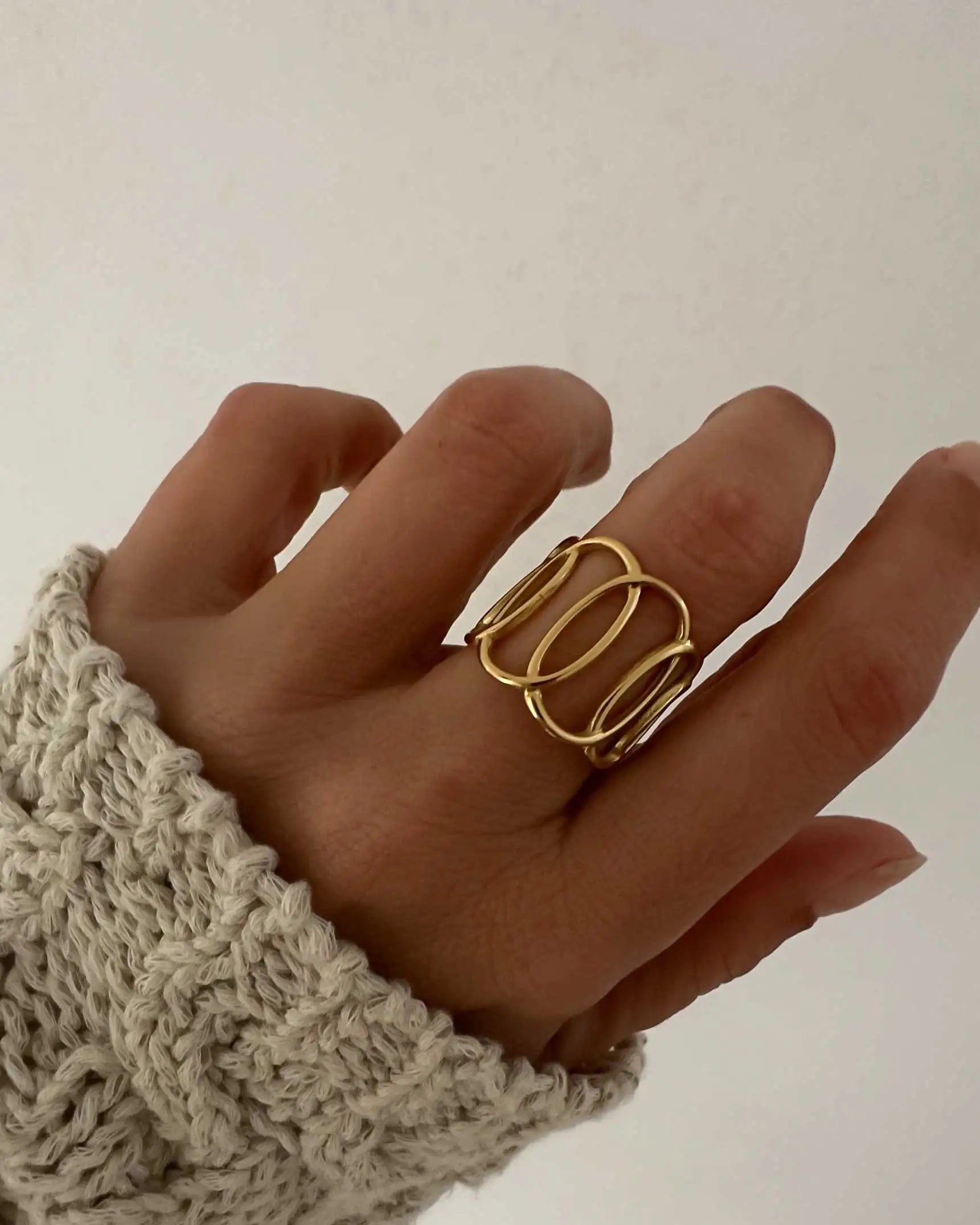 Anillo ajustable formado por óvalos entrelazados de acero inoxidable bañado en oro.